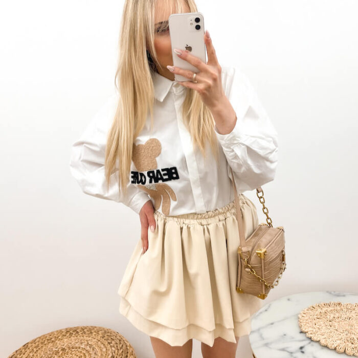 Młoda kobieta w białej eleganckiej koszuli i krótkiej beżowej spódnicy