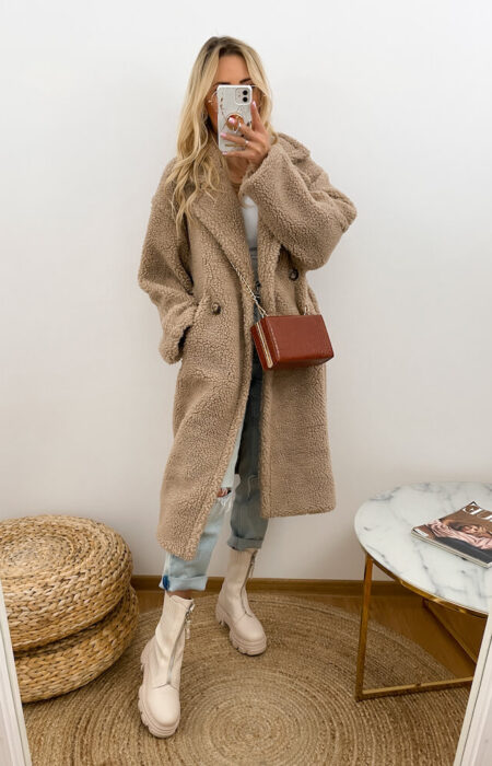 Młoda kobieta prezentuje zimowy płaszczyk teddy i białą koszulę