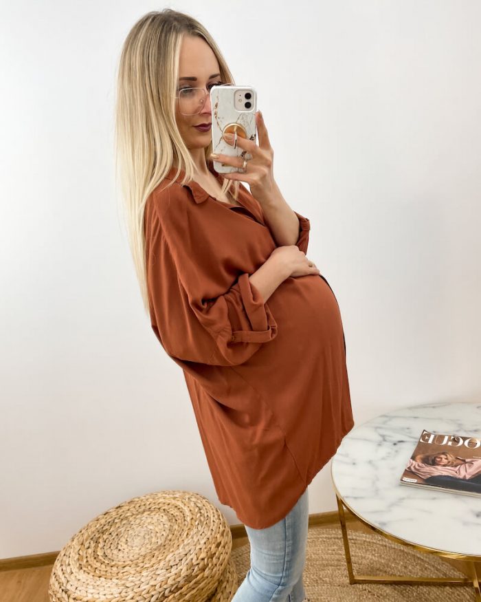 Koszula ciążowa w kolorze brązowym prezentowana przez młodą kobietę