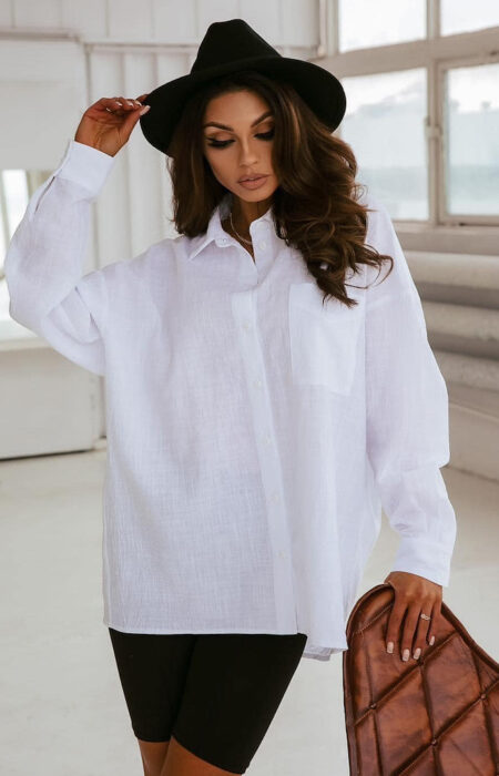 Młoda kobieta prezentuje biały elegancką bawełnianą koszulę z czarnymi kolarkami i kapeluszem