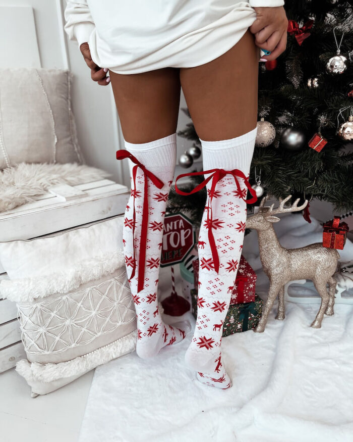 Młoda dziewczyna prezentuje zakolanówki świąteczne w norweskie wzory białe z kokardą