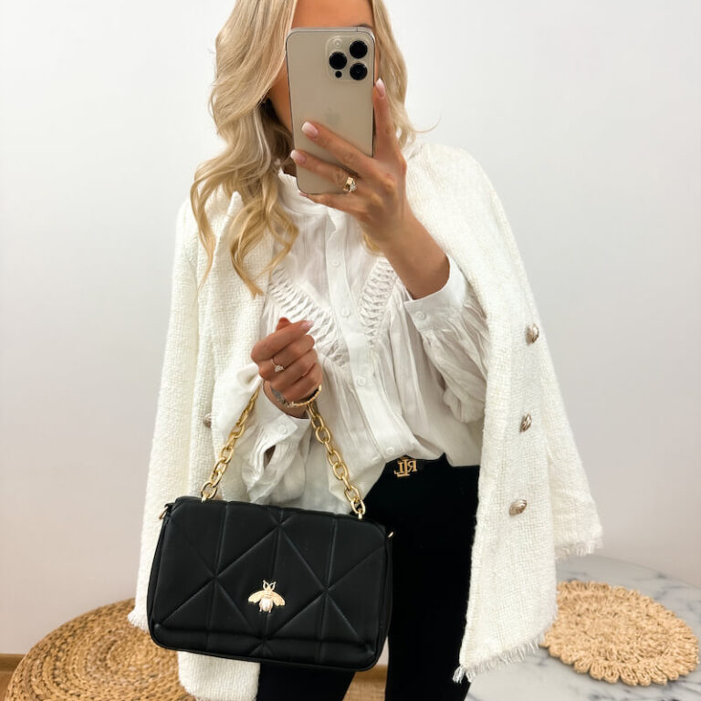 Czarna torebka damska na łańcuszku z muchą prezentowana przez młodą dziewczynę