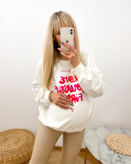 Bluza ciążowa biała oversize z napisem Love Yourself First prezentowana przez młodą mamę