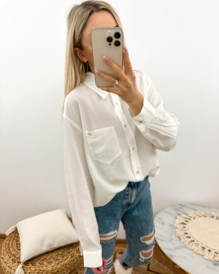Biała koszula damska oversize na guziki prezentowana przez młodą dziewczynę