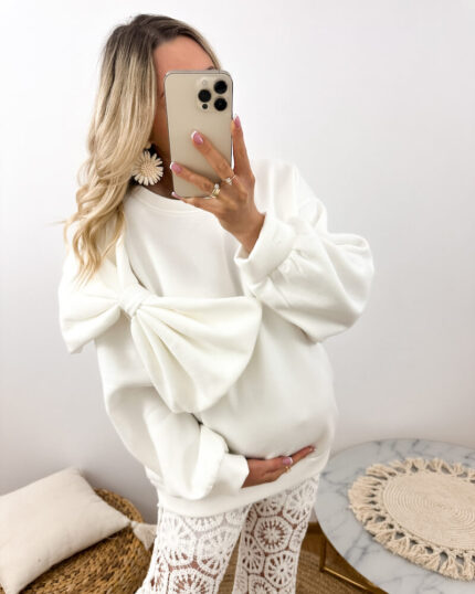 Biała bluza ciążowa z kokardą oversize prezentowana przez młodą mamę