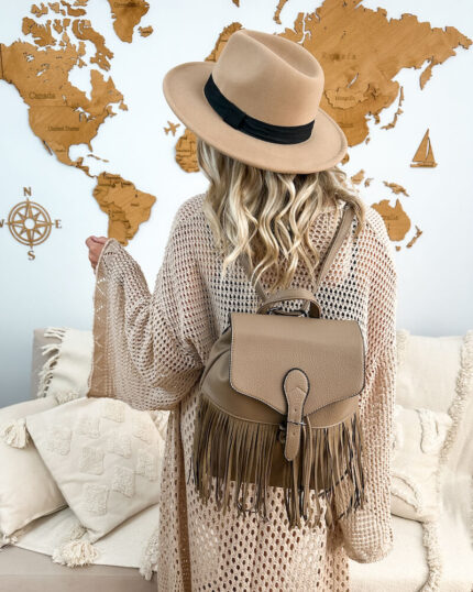 Beżowy plecak z frędzlami w stylu boho prezentowany przez młodą dziewczynę