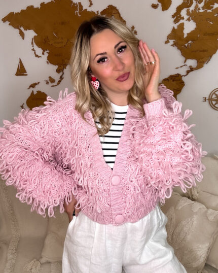 Różowy kardigan z frędzlami boho prezentowany przez młodą dziewczynę