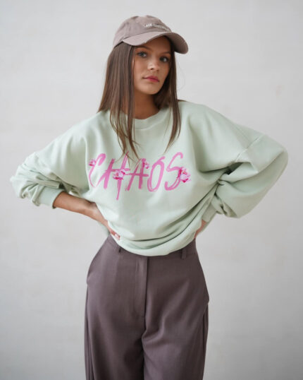 Pistacjowa bluza overisze z napisem CHAOS prezentowana przez młodą dziewczynę