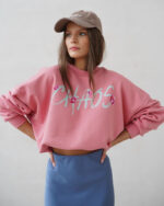 Różowa bluza overisze z napisem CHAOS prezentowana przez młodą dziewczynę